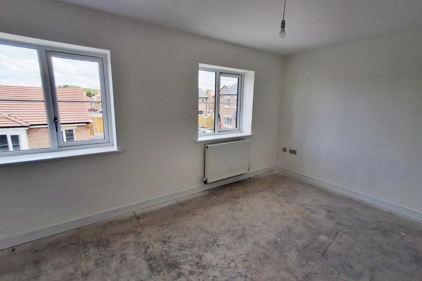 One of the upstairs bedrooms showing two windows, a radiator, and two electric plug sockets