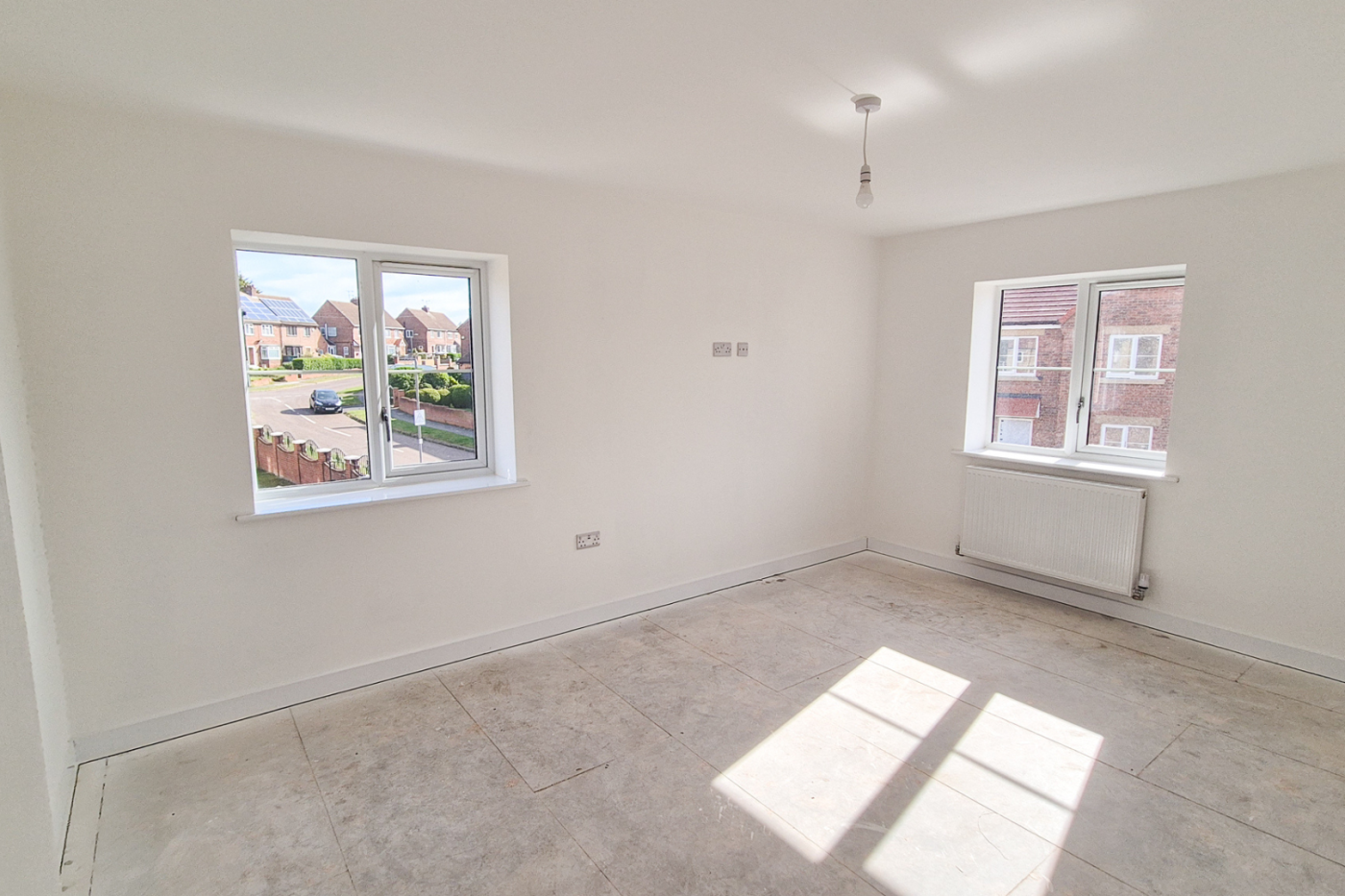 The bedroom showing two windows, the bedroom floor, one wall socket near the floor and one higher up