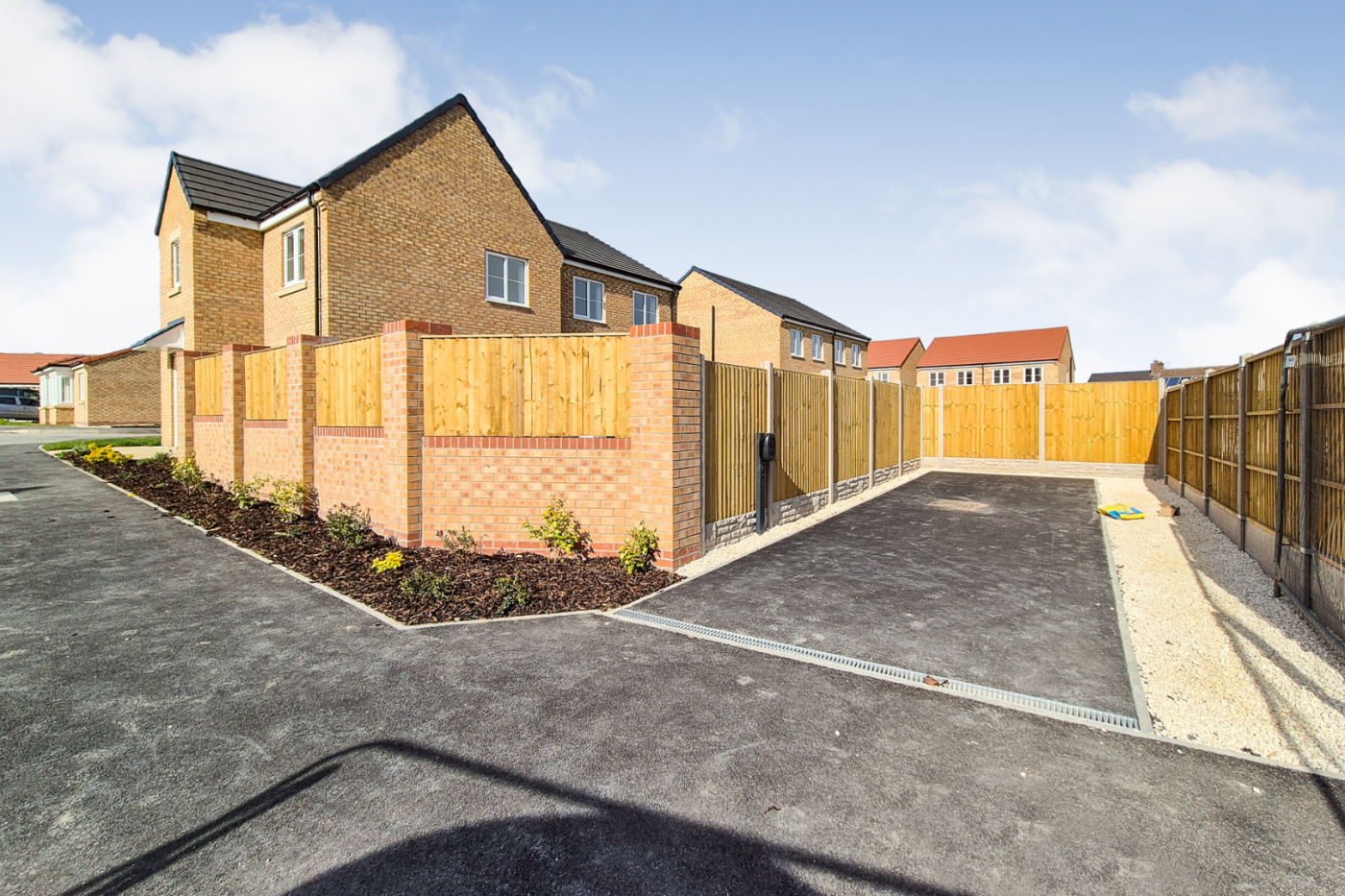 The driveway which has space for two vehicles and has an electric charging point. The driveway is surrounded by a fence on three sides.
