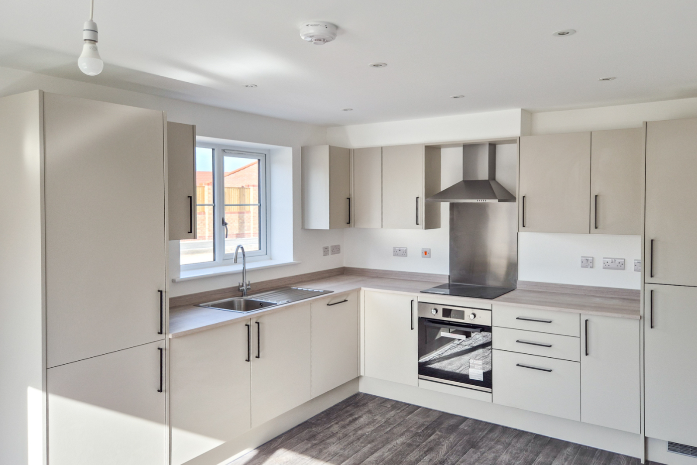 The kitchen showing flooring, a cooker, hob, sink and cupboards.