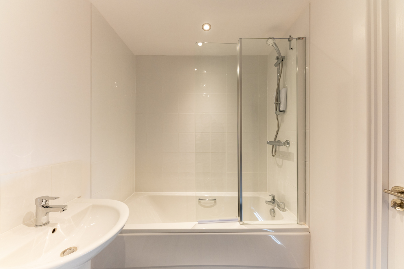 A bath with shower and sink in a bathroom