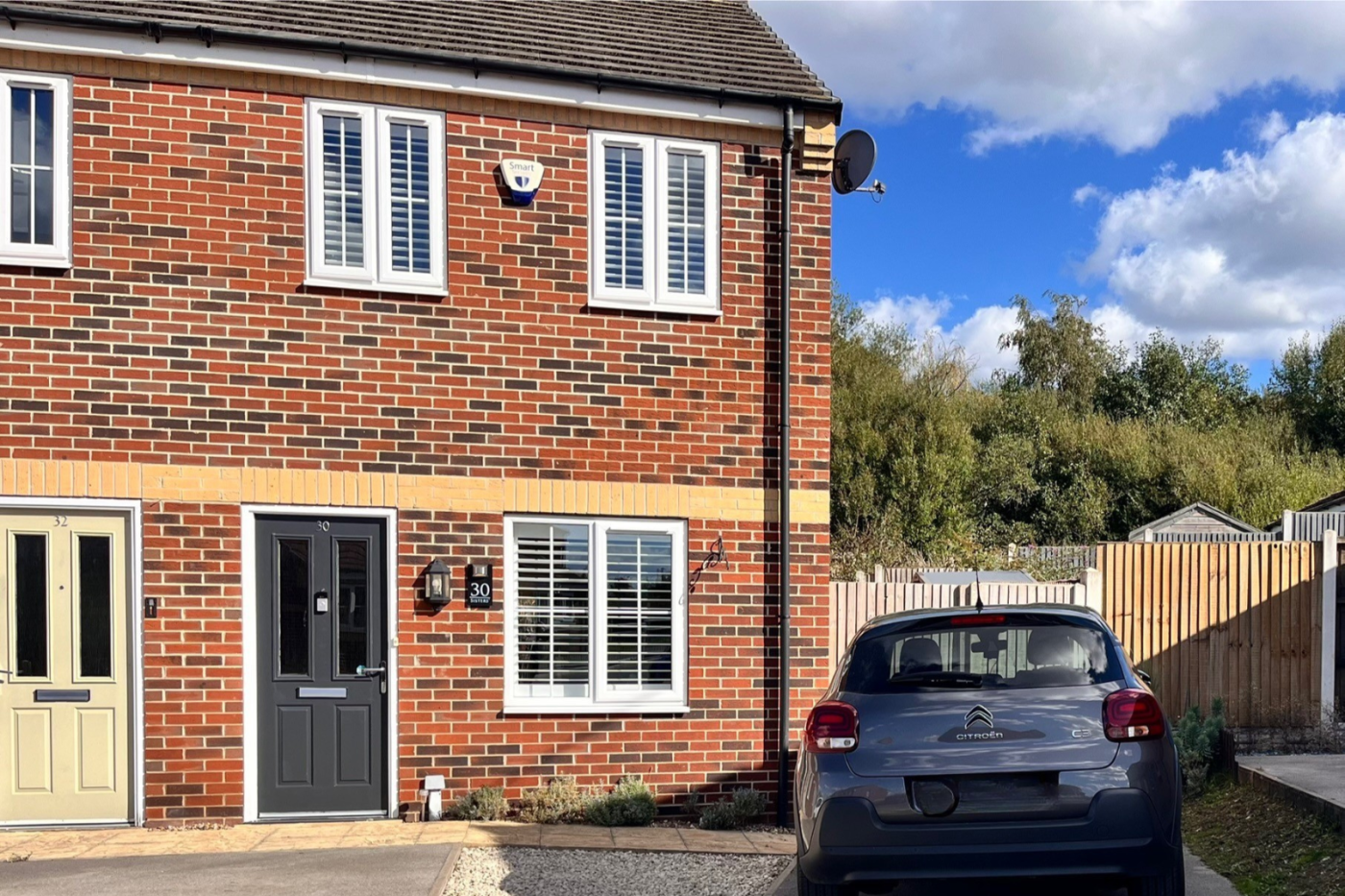 front of a semi detached house with a car parked outside