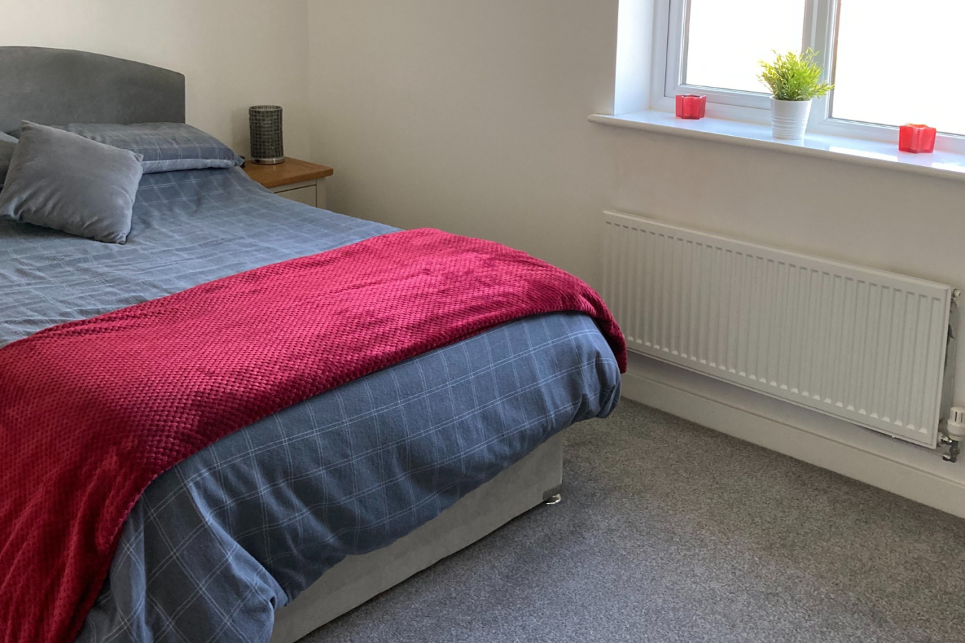 A photo of a bedroom showing the bed and a light grey carpet