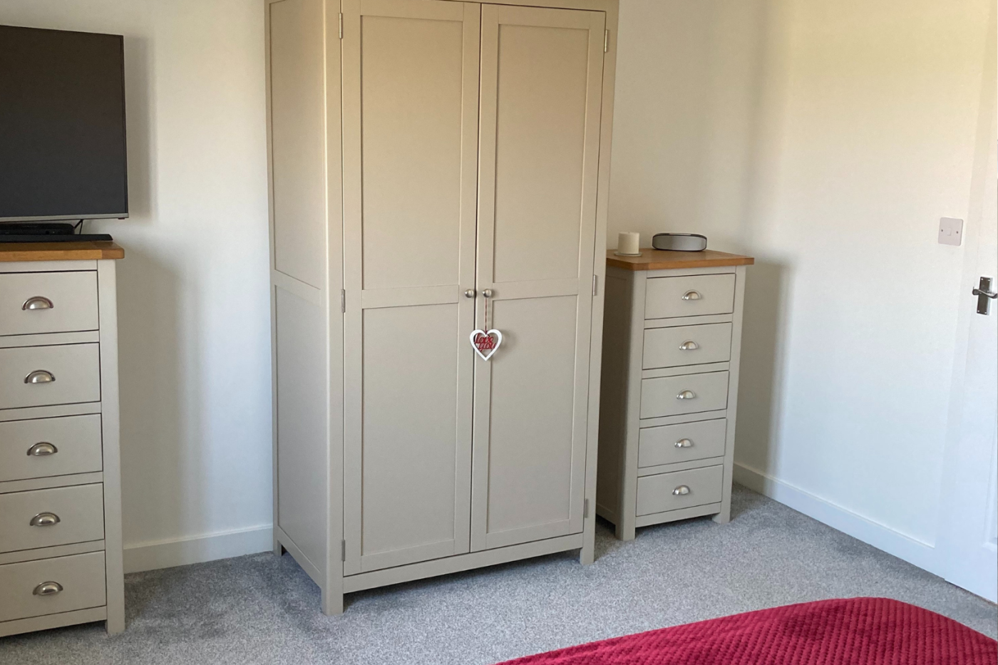 A photo of a bedroom with a light grey carpet showing a wardrobe and drawers