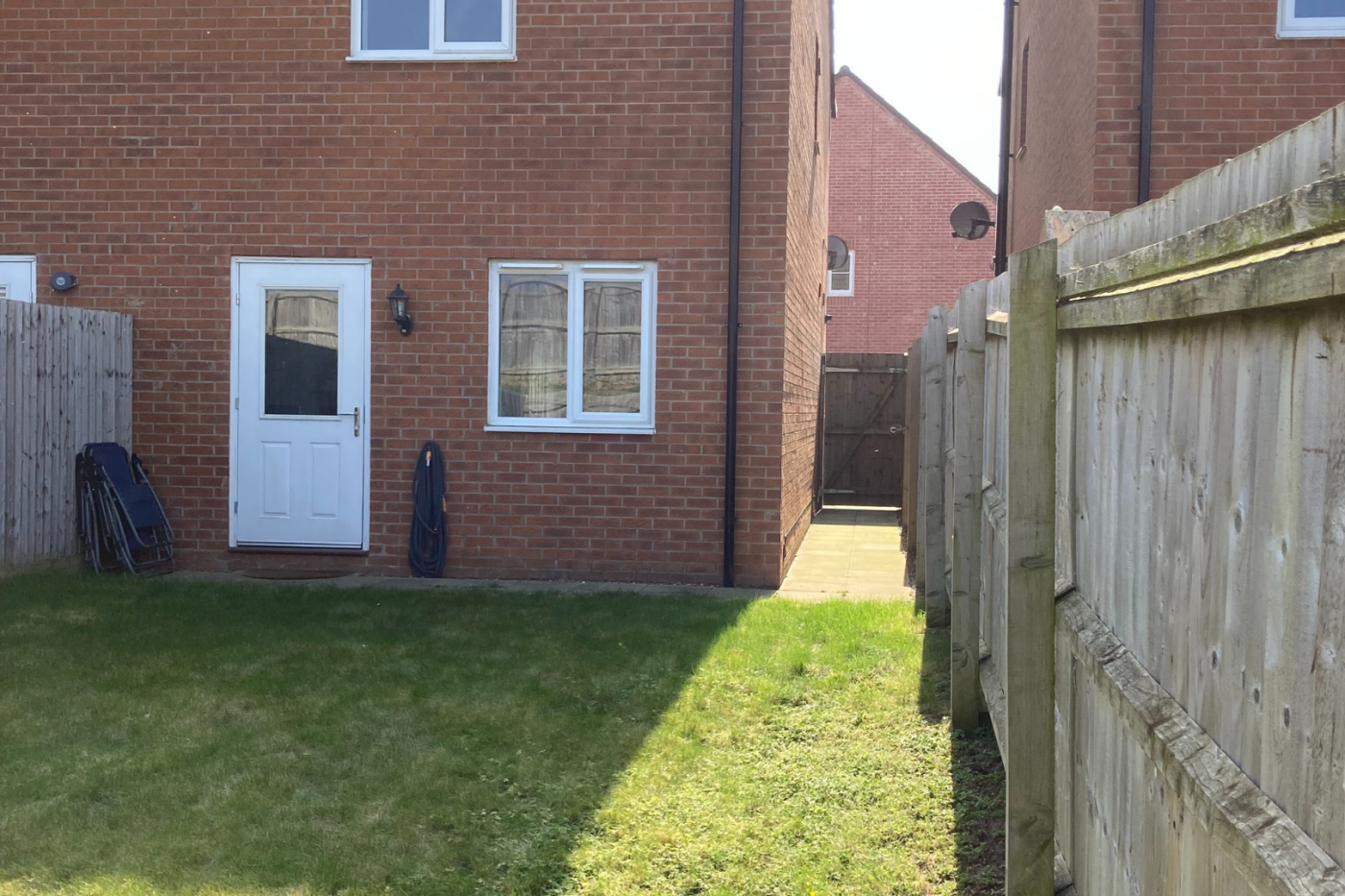 A photo of the garden showing the grass, back door, and gate
