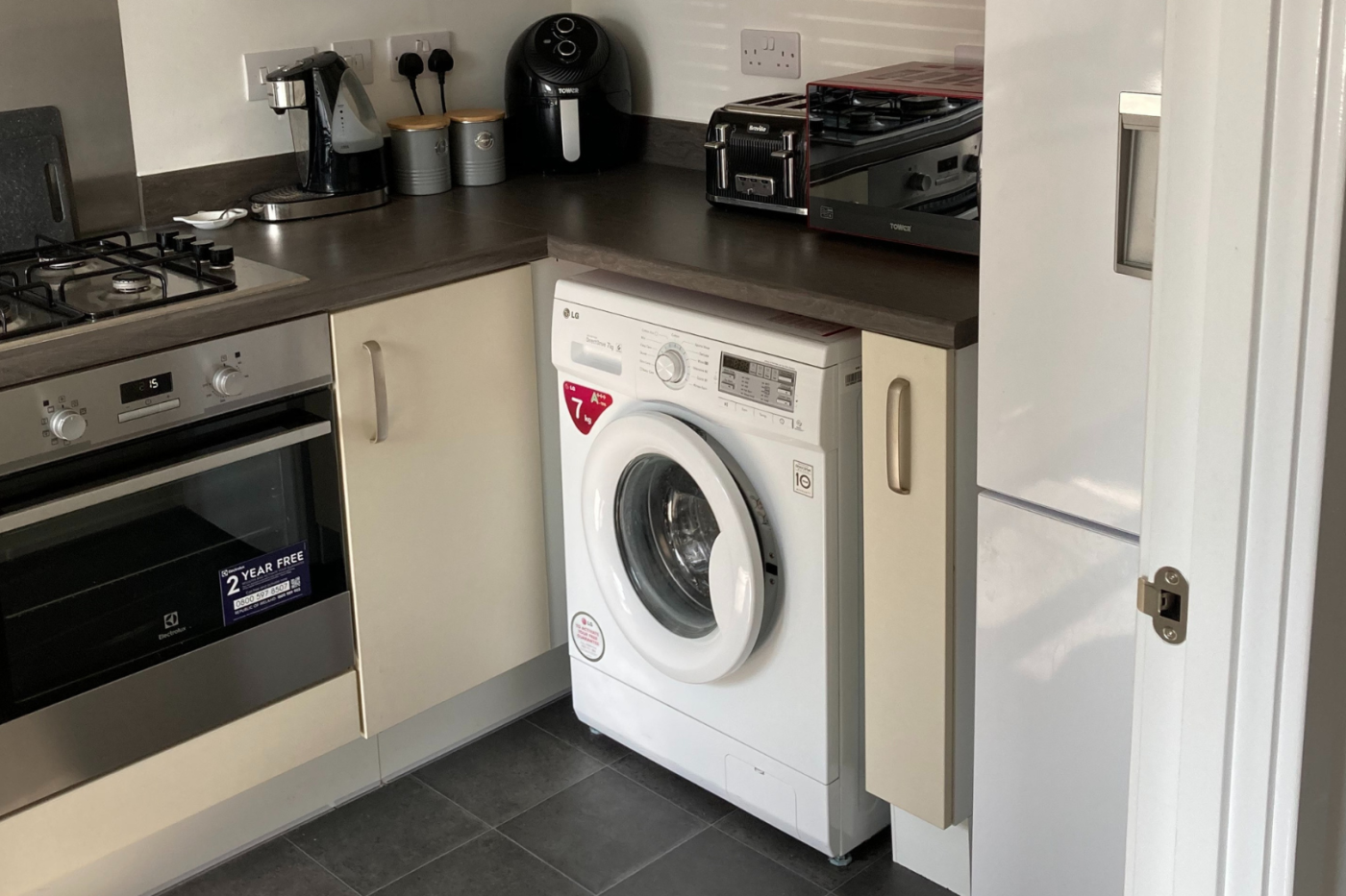 A photo of the kitchen showing a washing machine and cooker