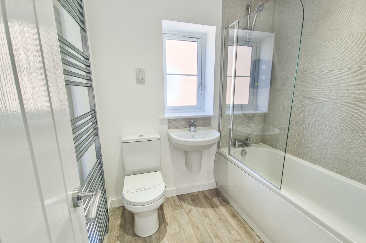 The upstairs bathroom showing bath, shower, sink and towel radiator