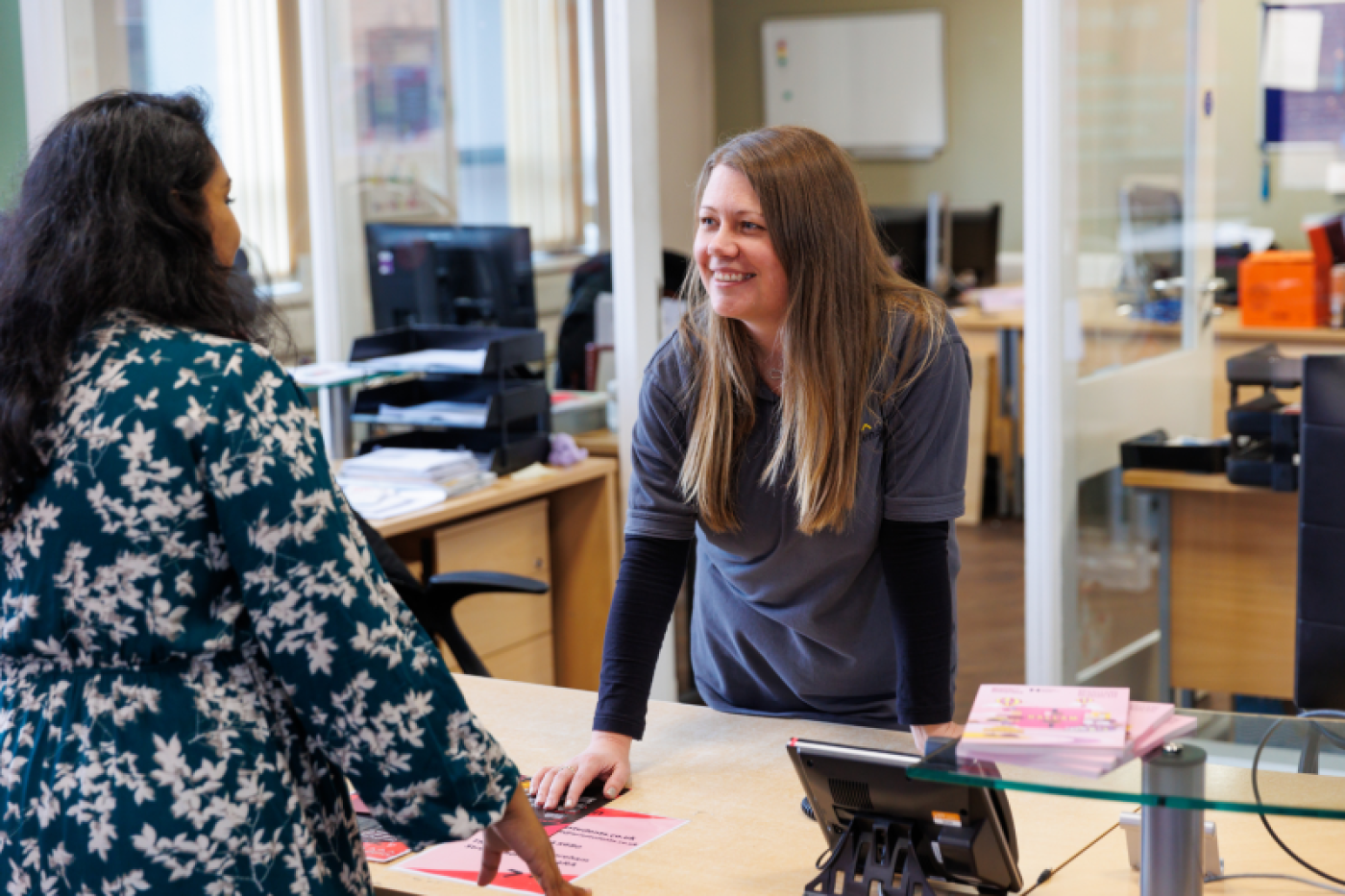 Two women chatting at student support service desk