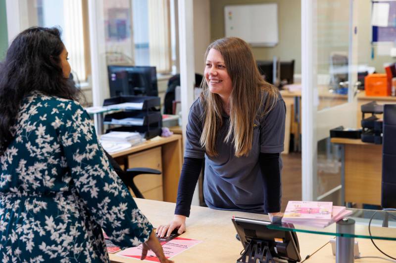 Two women talking over a reception desk