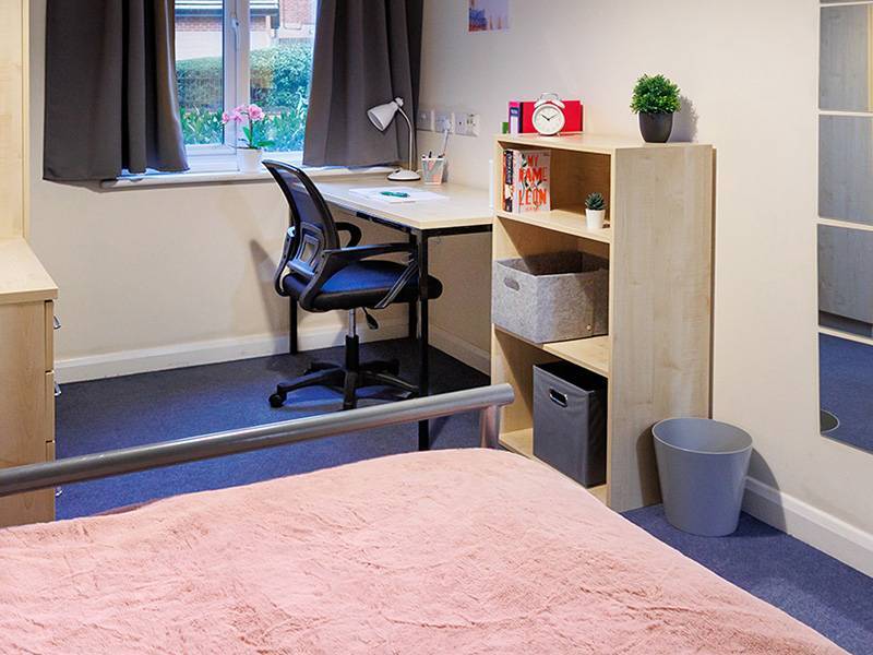 Student room with bed, desk, chair and window
