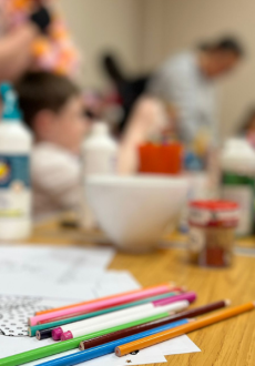 colouring sheets and pencils with people in the background