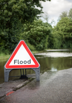 An image of a flooded road with a triangle flood sign.