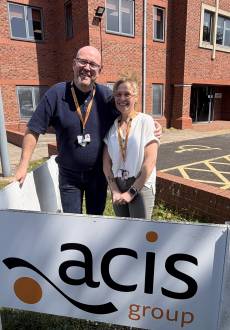A man and woman stand side by side outside Acis Group's business office