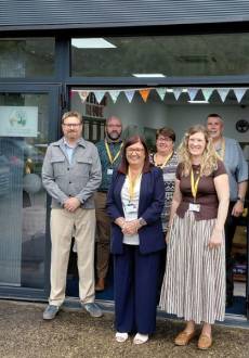 A group of staff smile as they stand outside of a new Wellbeing and Learning Hub