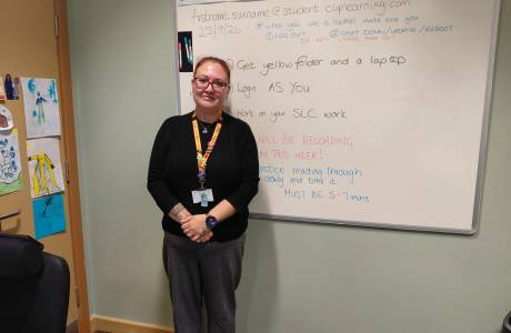 Woman stood alone in a classroom smiling