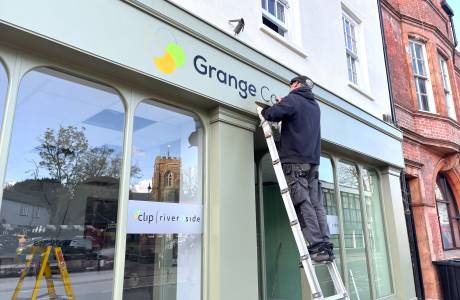 A man paints a sign on a shop front