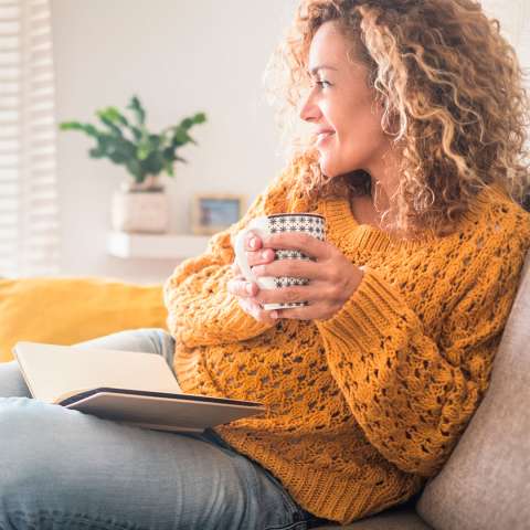 Woman sitting on sofa with a hot drink