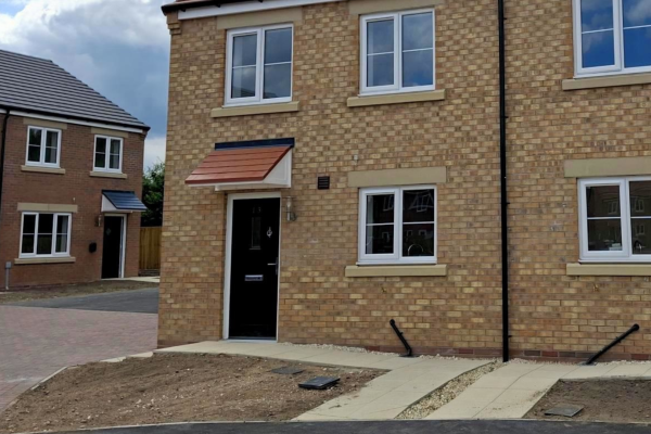 The front of the house showing a black door and three windows