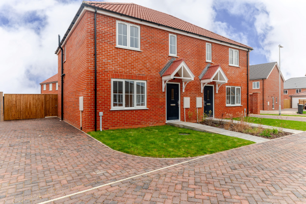 Side on view of a semi detached house with parking and a lawn at the front.