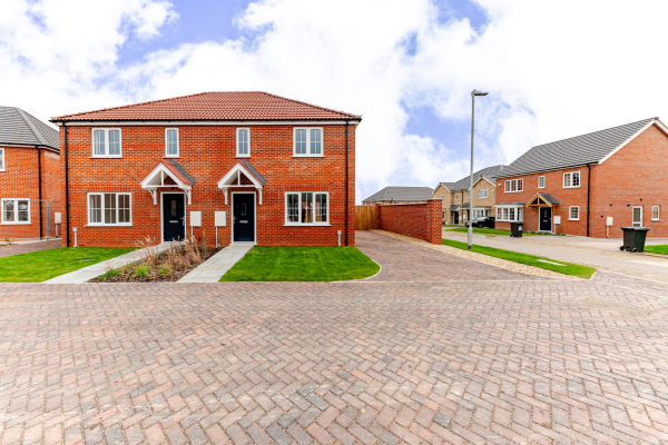 Side on of a semi detached house with parking and a lawn at the front.