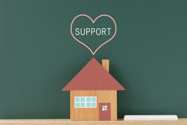 House made of cardboard with support written in heart above