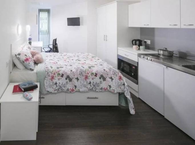 studio bedroom with bed and kitchen