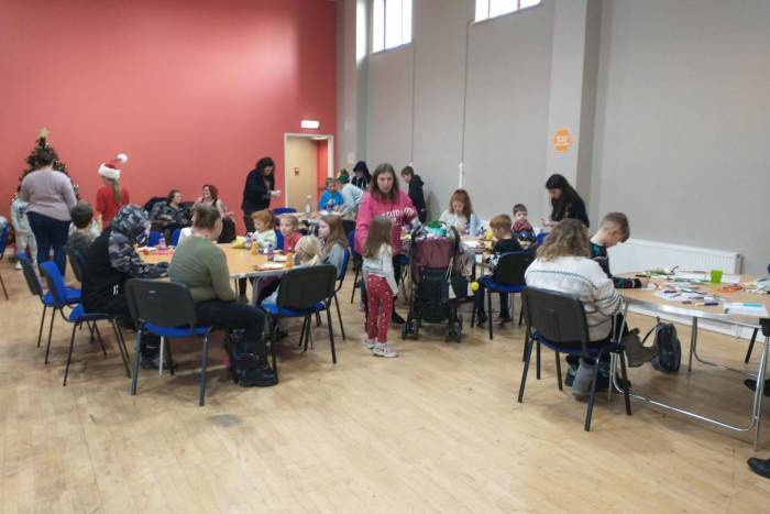 Families sitting at tables making Christmas crafts