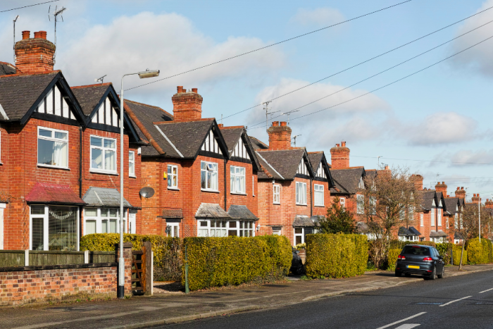 A row of houses with cars parked on the road