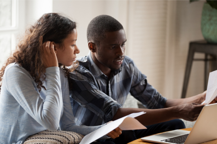 Two people looking at a bill with a laptop