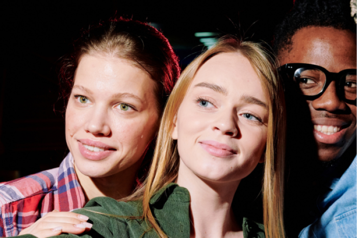 Two women and one man looking at a camera 