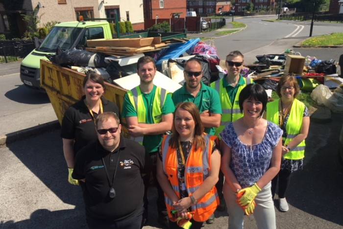 Group of people standing in front of full skips