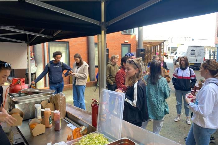 students stood chatting and getting burgers from food truck
