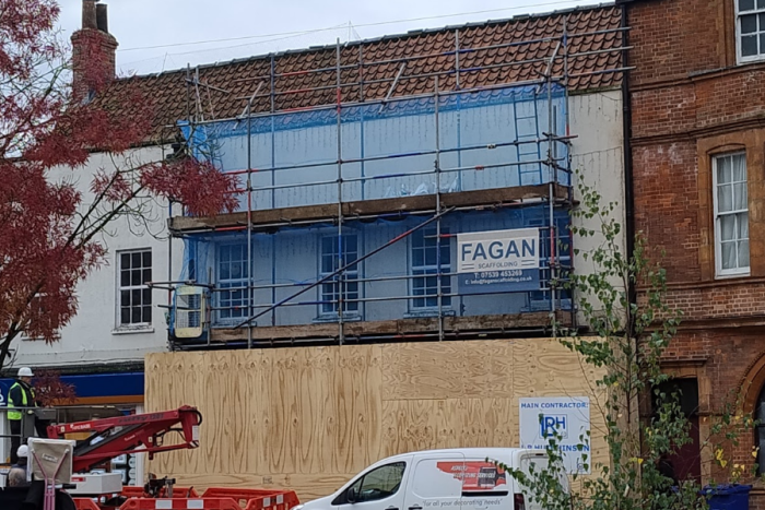 The outside of a building with boarding and scaffolding. 
