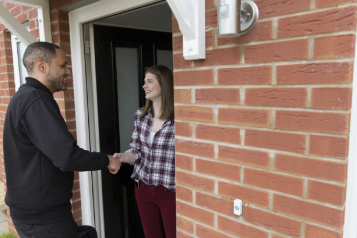 An engineer shaking a lady's house on her doorstep.