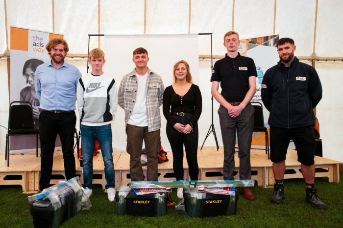 Six people stood smiling with tool kits