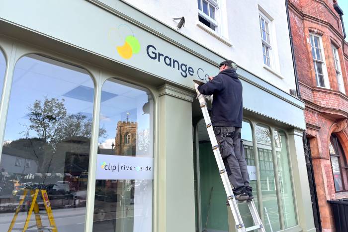 A man paints a sign on a shop front