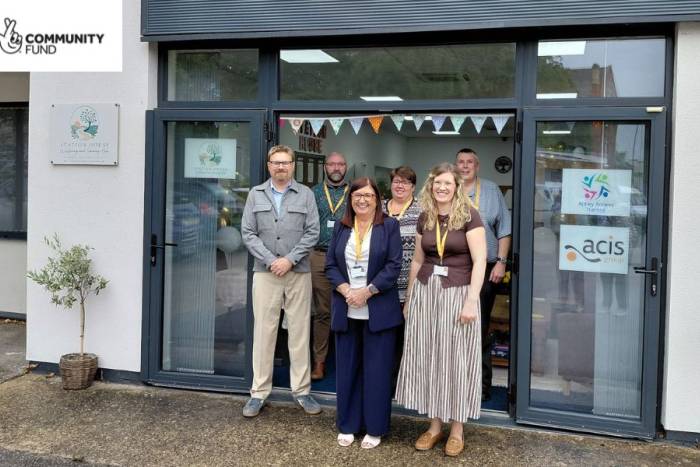 A group of staff smile as they stand outside of a new Wellbeing and Learning Hub