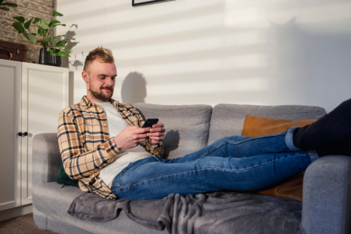 A man on his phone sat on the sofa