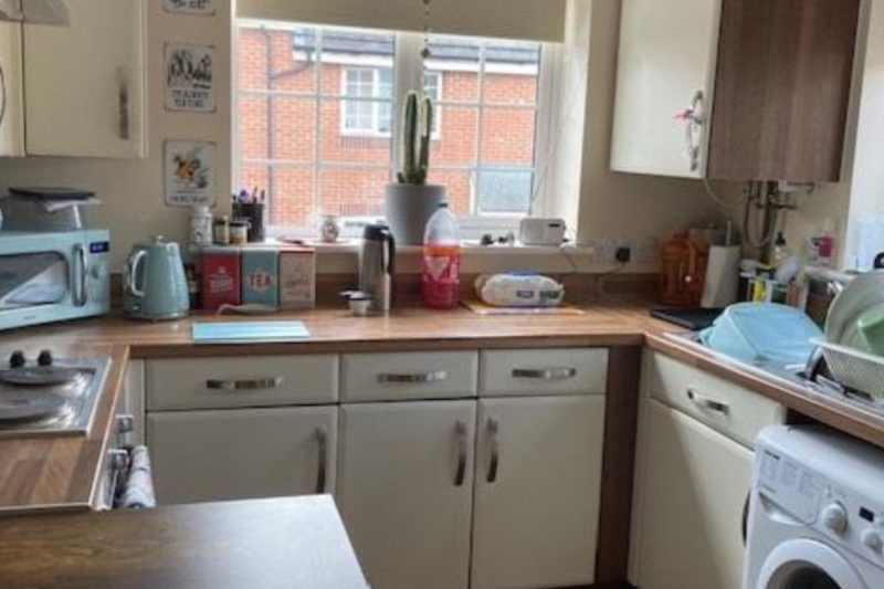 Kitchen with items on the work surfaces and a window