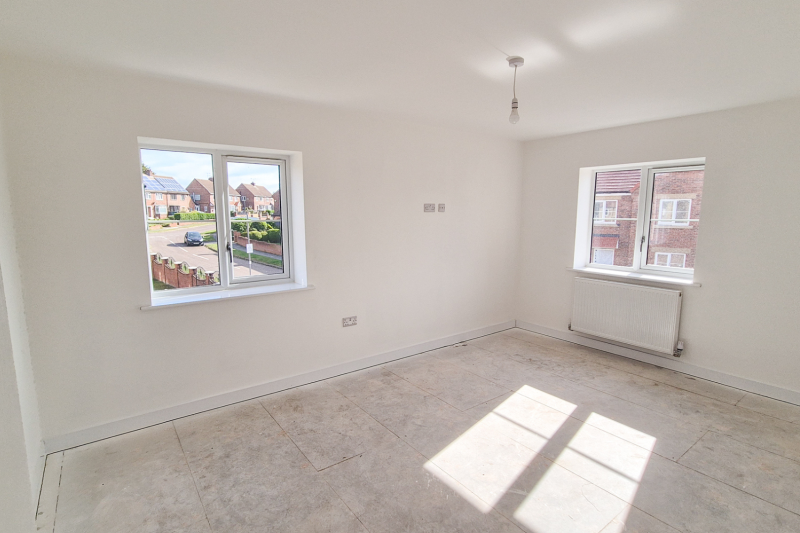 The bedroom showing two windows, the bedroom floor, one wall socket near the floor and one higher up