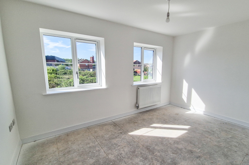 A bedroom with two windows and a radiator