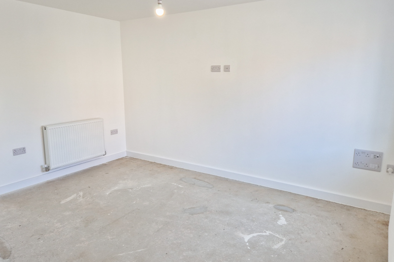 The lounge showing a radiator and several plug sockets on the wall, some lower down and some higher up for a television connection