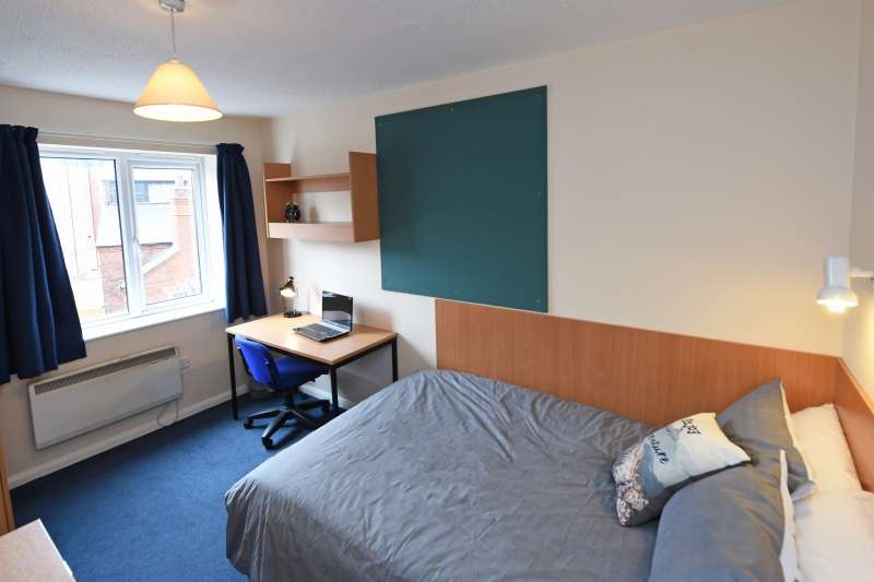 Bedroom with bed, desk and notice board