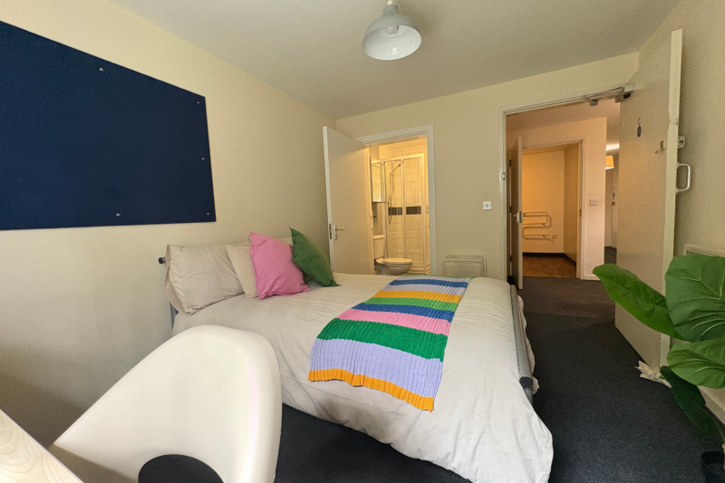 Bedroom with bed, desk, wardrobe and notice board
