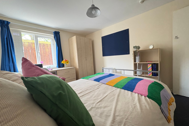 bedroom space with 3/4 bed, wardrobe and desk