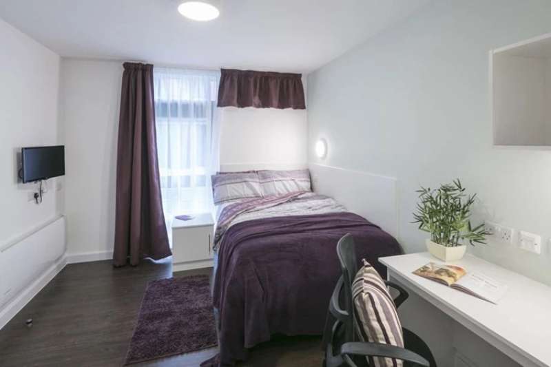 Bedroom with bed, desk and chair and television on the wall