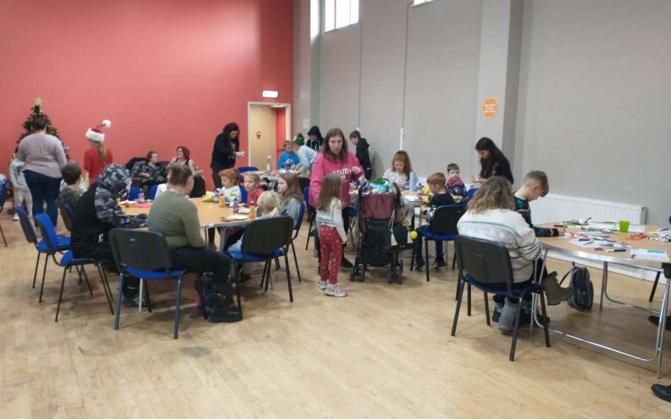 Families sitting at tables making Christmas crafts