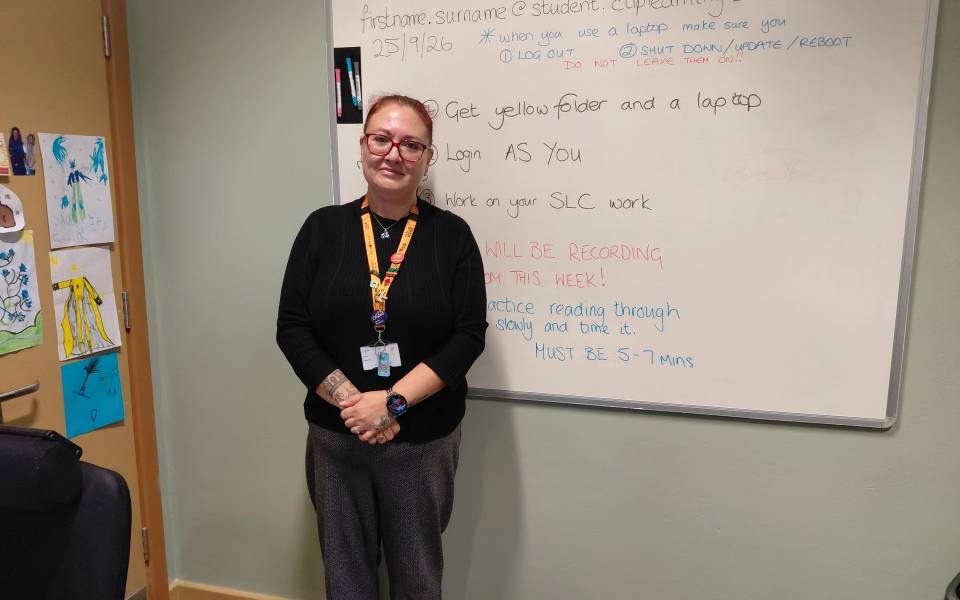 Woman stood alone in a classroom smiling