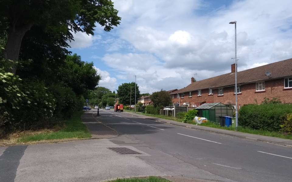 A street in the sunshine with houses and cars