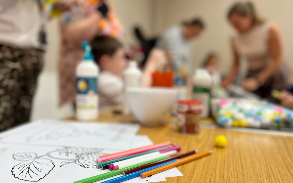 colouring sheets and pencils with people in the background